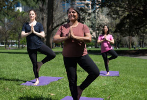 Three women practicing yoga in the park.