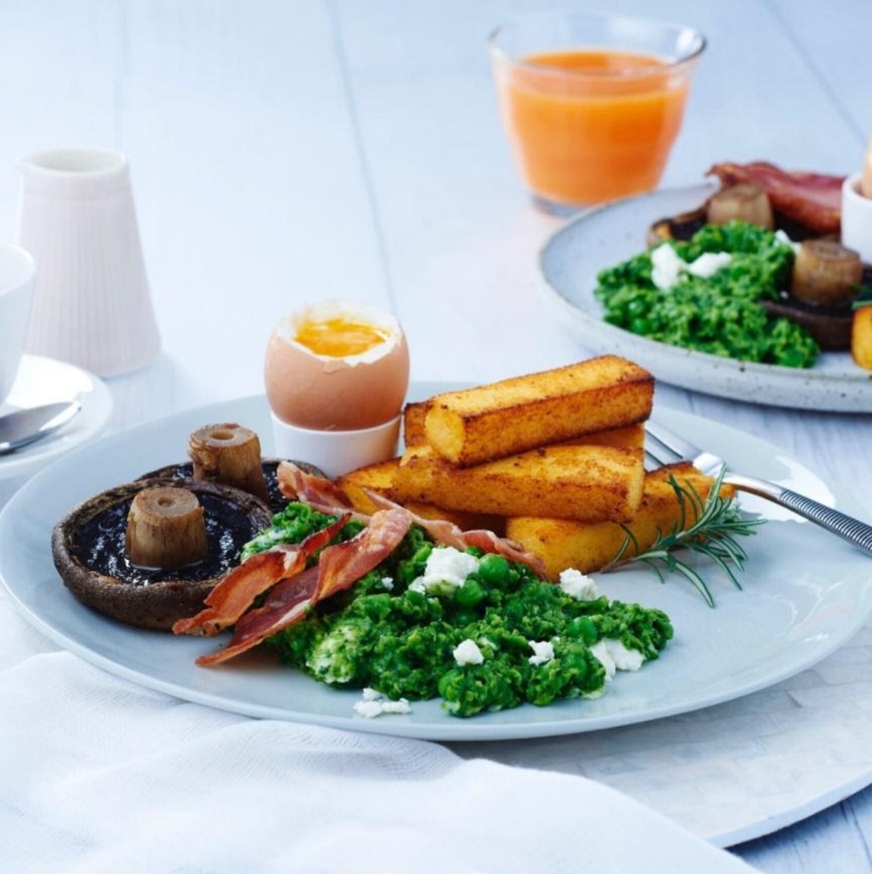 Breakfast plate with boiled egg, polenta chips, mushrooms, pancetta, baby spinach, peas and fetta cheese.