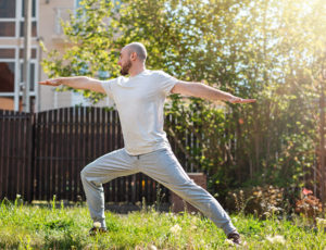 A man practising yoga at home in his garden.