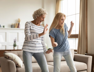 An older woman and a younger woman dancing in their living room.