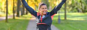 Woman dressed in activewear, smiling with her hands up in the air.