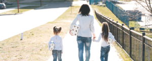Woman and two daughters walking home from supermarket with toilet rolls