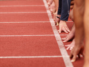 A range of hands waiting at the start line of an athletics track